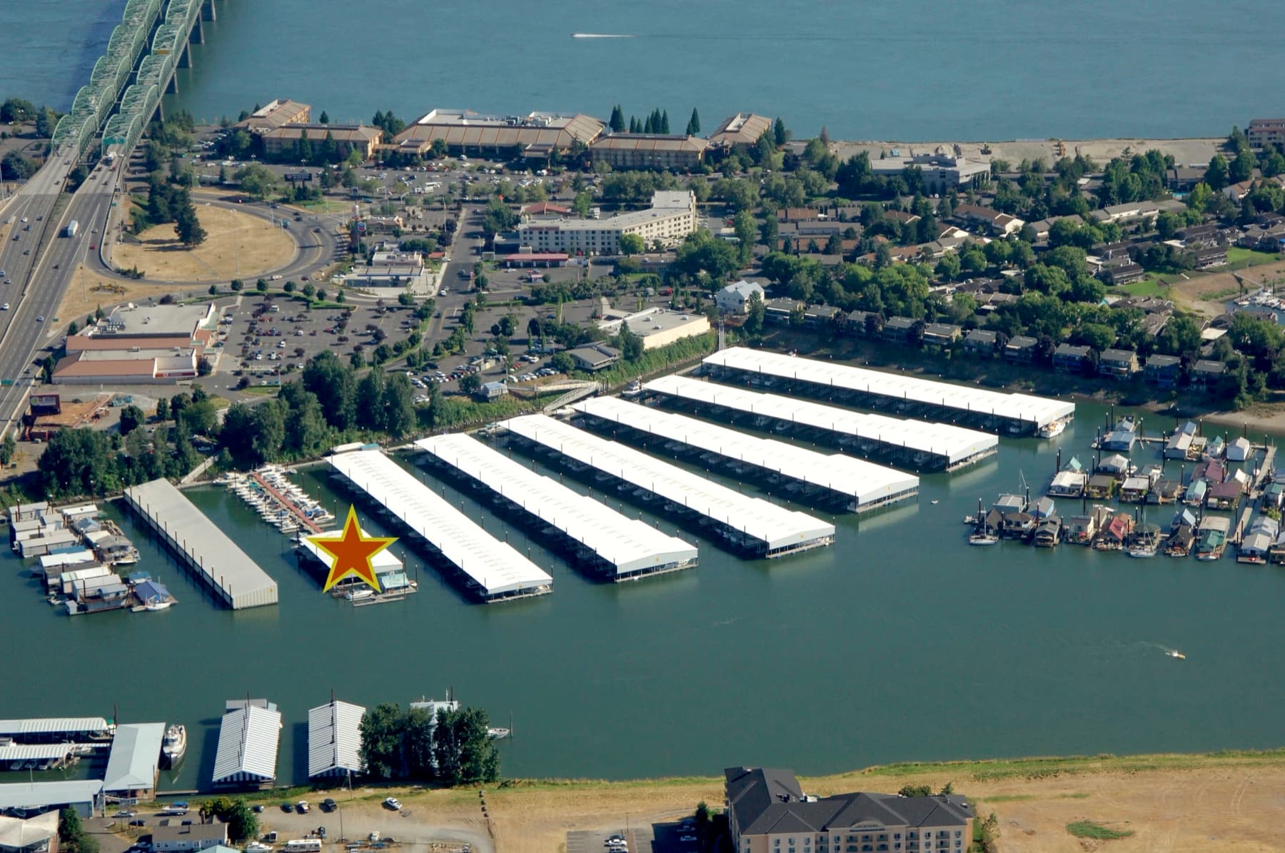 Aerial view of the Hayden Island marina with a star marking the exact building where Jantzen Fuel Depot sits among the covered boat slips